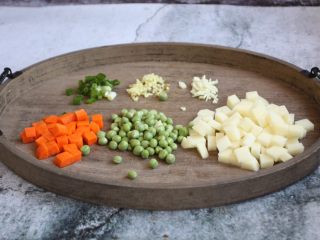 6、咖喱土豆鸡丁饭,将土豆切成丁、胡萝卜切成丁、豌豆清洗干净，葱切成葱花、姜切成姜末、蒜切成蒜末。