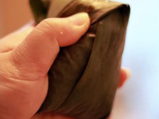 10、五花肉粽,余下的粽叶翻上去覆盖整个粽子，注意边角要折好，不然煮的时候糯米就会露出来了