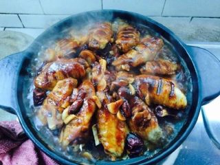 7、三汁鸡翅焖锅,焖煮20分钟，刷酱汁，在鸡翅上面洒少许的辣椒面，加入枸杞、红枣。继续焖煮5分钟（为了更加入味，可以将切好的蒜片洒在上面）