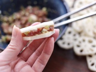 7、藕夹肉,取一个藕夹,中间塞入适量的馅料,用手把两片藕轻轻捏一下,让馅料和藕夹更熨帖。