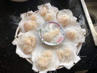 4、粉丝蒸扇贝,用剪刀将粉丝剪断，垫在贝肉下面。