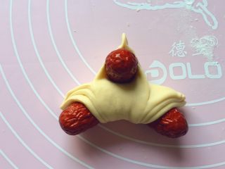 13、吉祥枣花馍,如图：翻过来，把第一张面片捏起来，中间放上一个红枣。