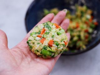 12、低脂杂粮谷物时蔬饼,取一块搅拌好的馅料，用手先揉圆后摁扁。
