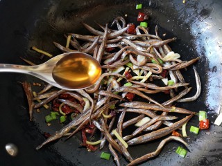 7、十味 香辣小鱼干,然后加入2勺料酒继续翻炒。