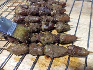 11、孜然烤鸡心串,鸡心串烤10分钟后取出来,逐个将鸡心串刷上调好的孜然汁。