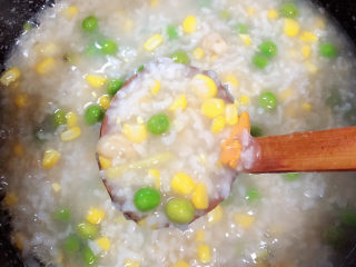 12、冬日暖心菜 扇贝田园砂锅粥,盖盖儿继续小火炖,时不时搅拌一下,避免糊底。扇贝肉小火儿熬制5-8分钟即可。