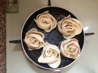 23、玫瑰花抱蛋煎饺,放入玫瑰花饺子，中小火煎制一分钟。倒入三分之一的水，盖上盖子焖至水干。