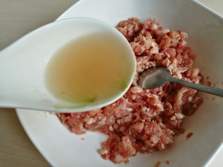 7、荠菜元宝水饺,放凉后的花椒水分次加入肉馅中。每加一次花椒水，都要把肉馅顺着一个方向搅打上劲，每次都要等水分被吸收了，再加下一次花椒水。