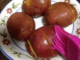 1、培根风琴烤土豆#辣味#,摆入盘中表面刷少许食用油（烤的时候油的渗入既可以防粘也可以滋润土豆）