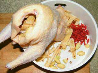 3、猪肚鸡汤,把鸡脚鸡头斩掉，除了枸杞以外，填入一半铺料