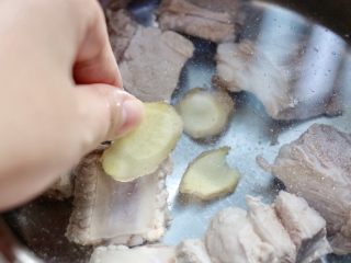 3、藕丁黑木耳炖排骨,排骨焯水后捞出沥干，锅中倒入清水，加入3片姜