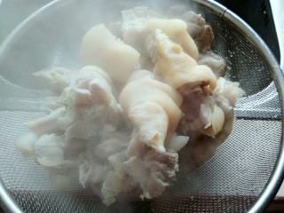 9、黄豆炖猪蹄,将猪蹄捞出，用温水洗洗，倒入漏盆中。