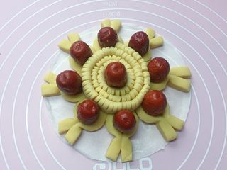 13、招财进宝枣花馍,把切好的长条卷起来，中间放一个红枣，然后放在枣花馍的中央位置，如上图。