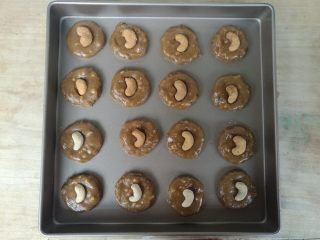 7、黑糖腰果酥,分成16份，用手揉成圆球，按扁，表面装饰一颗腰果。排入烤盘。