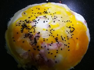 11、#感恩节食谱#培根蛋饼,鸡蛋快凝固时，撒点黑芝麻。翻面，过会出锅。