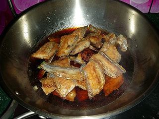 8、红烧带鱼,放带鱼块、再倒入生抽、老抽和温水加盖大火