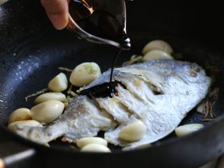 8、蒜香鲳鱼,再次放入鲳鱼，调入红烧酱油一汤匙、黄酒一汤匙。