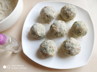 14、糙米薄皮菜团子,然后用一个小喷壶，往沾了第一遍糙米粉的菜团子上喷水，将表面的糙米粉打湿。