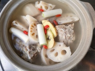 8、莲藕脊骨汤,加入莲藕,葱姜枸杞和足量的水(如果煮的过程中水实在太少可适量加入温水或热水),先大火煮开再转中小火加盖煮1-1个半小时。(在熬制骨头汤时,中途不要往锅中加冷水,否则,汤温骤然下降,会使骨中的蛋白质等迅速凝固而变性,收缩成团而不再解聚,肉质表面的空隙也会因此而收缩,造成肉骨组织紧密不易焖酥,骨髓内的蛋白质、脂肪无法大量溶出,这样不仅影响汤中的营养含量,而且也影响汤味的鲜香程度)