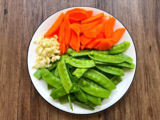 4、荷塘小炒,荷兰豆掐掉头尾,清新干净,胡萝卜刮掉外皮,切成薄片,蒜去皮洗净切末待用。