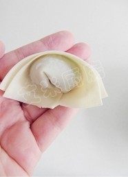 17、荠菜猪肉馄饨,然后将下边的两个角捏合在一起。一般在市场买来的馄饨皮都比较干，可以在馄饨皮上涂一点清水以便于馄饨皮的捏合