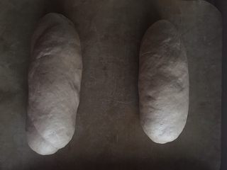 10、红糖核桃红枣软欧--无比美味,卷好，两边收口捏紧，摆上烤盘盖上保鲜膜最后发酵