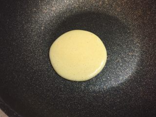 7、奶香玉米饼,不粘锅烧热,保持小火,不放油,舀起一勺玉米面糊,从约30厘米处低落,自然形成圆形。每舀一勺的量要相同,确保每个饼的大小一致。