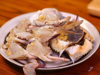 1、梭子蟹年糕,首先我们把洗干净的梭子蟹，从尾部掰开，剪掉里面的毛腮，然后再把蟹从中间切半，再切半，两个大钳子分别用刀背敲开，这样烧出来更入味