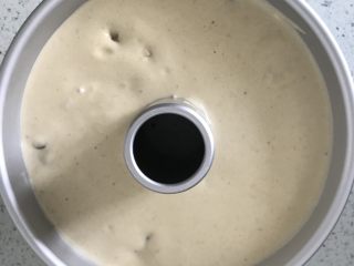 19、红枣戚风蛋糕,打蛋盆离中空模具20厘米高倒入18厘米中空模具中,这一步的目的是为了把个别大气泡拉抻破掉,两个大拇指按住中空柱大力振几下模具,把大气泡震出来。