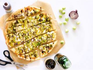 5、啤酒洋葱抱子甘蓝披萨,在披萨面团上抹橄榄油 ，撒上红洋葱碎，马苏里拉芝士碎 ，菲达芝士块 和抱子甘蓝 。