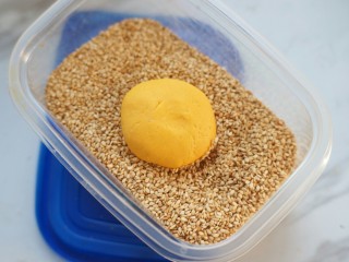 15、南瓜夹心苏打饼,在白芝麻里滚一圈,让面团蘸满芝麻,再轻轻按压,使芝麻与面团贴合。
