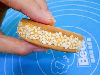 10、南瓜饼,取另一块饼干盖在面团上，将面团夹在中间，形成夹心，然后把饼放在芝麻里滚一圈，让饼周围都均匀的沾上芝麻