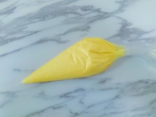 9、蛋黄饼干,将混合好的面糊倒入裱花袋中,然后用剪刀在裱花袋口处煎一个小口