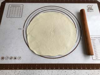 4、秋葵肉肠披萨,取出面团，擀成比披萨盘大一圈的面皮