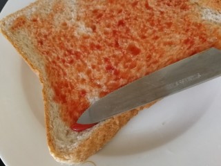 7、吐司培根披萨,吐司底层涂一层番茄沙司。同时烤箱170度预热10分钟。