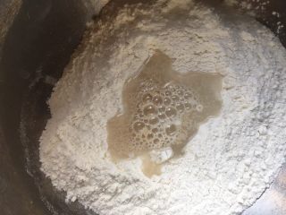 3、一次性发酵简单易做葱花卷,挖一个坑倒入酵母加一些水和匀