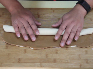 7、自制猫耳朵,然后从一边卷起，卷成实心。包上保鲜膜放冰箱冷冻40分钟以上。（也可以不用保鲜膜）