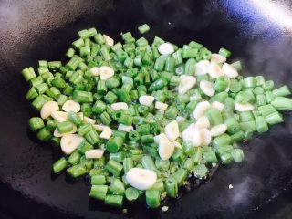 8、四季豆时蔬丁虾仁小炒,四季豆煸炒到5成熟时放入蒜片一起煸炒。