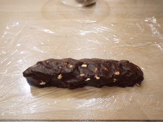 17、可可坚果,将拌好的面团放在保鲜膜边缘,稍稍摆成长条形,卷起保鲜膜,手工整成长方形条(压紧压实)有饼干膜的直接用膜具。