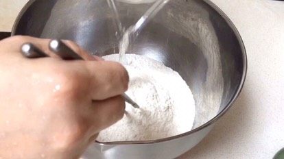 1、炸酱面·#人民的美食#,将水缓缓加入面粉，边较快速用筷子搅动