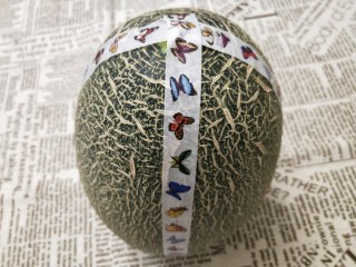2、水果花篮,用胶布将哈密瓜围绕一圈，再绕一半的一半，就是绕成四份