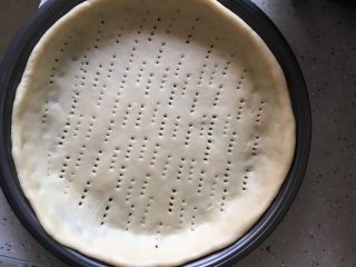 5、火腿披萨,将发好的面揉出空气，擀开放披萨盘，并插些洞洞