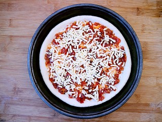 6、培根口蘑芝香披萨,在披萨酱上铺一层芝士碎。