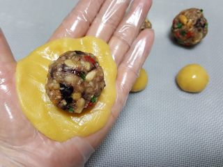 8、广式月饼~五仁馅儿,8．将一份馅料放在饼皮上，包裹馅料时，尽量避免饼皮与馅料中间有空气。
