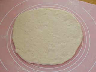 7、先煎后烤披萨,13.取一份面团抻成大饼，抻的水平有限就用擀面杖擀几下，就这样不规则的就好，不要擀的太圆，这就是这种披萨的特殊之处。