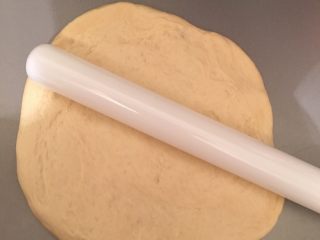 2、香肠芝士披萨,将面团用木棍推成饼底雏形。