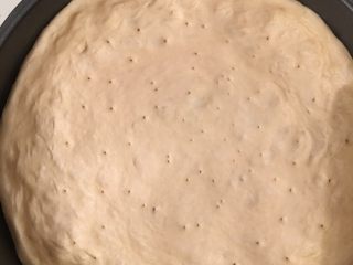 3、香肠芝士披萨,铺在披萨烤盘上,把圆边压厚些，中间要薄点。然后用叉子或牙签在饼底弄些孔来排气，以免烤的时候会膨胀起来