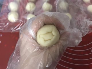 7、麻薯肉松蛋黄酥,用虎口慢慢将油皮往上推，右手拇指把油酥往下压，包住油酥