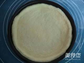 4、自制披萨,将面片放入披萨盘内,用手按压成四周厚中间薄的饼底