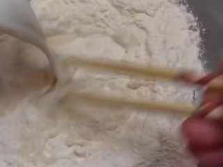 2、培根火腿披萨,用90ml的温牛奶搅面。